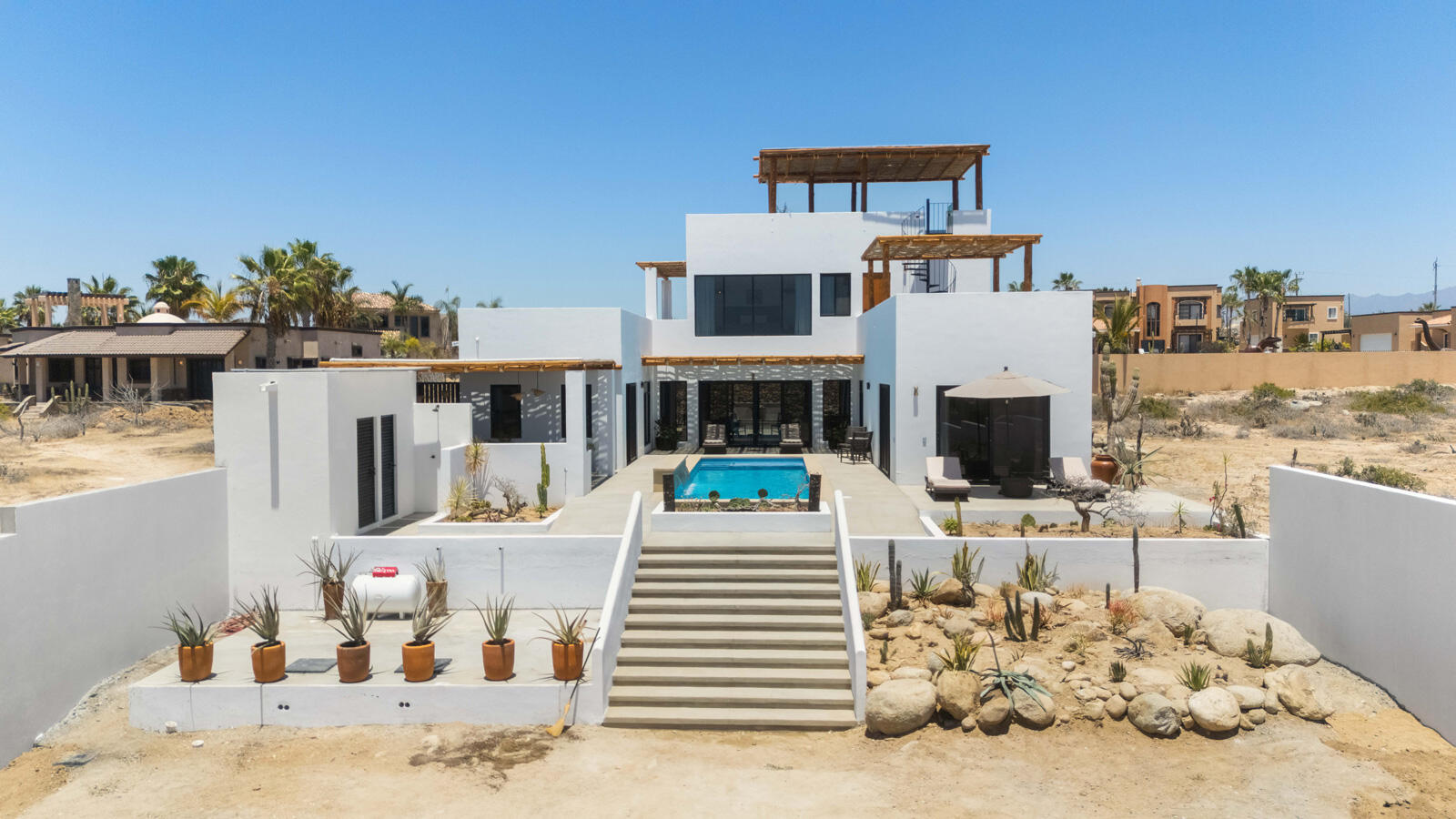 Chileno Bay El Posito We are excited to introduce Casa Elisabeth, an amazing, newly constructed custom home in the private El Posito area of Todos Santos. Located just three rows back from the beach, this three-bedroom, three-full and two-half bathroom residence offers every amenity desired for a tropical paradise. The downstairs features an open-concept living room, dining room, and a fully stocked kitchen with brand-new appliances, including a dishwasher. The main floor also includes a laundry room and an outdoor water feature with a professionally designed rock wall. The principal bedroom downstairs offers a unique indoor/outdoor bathroom with two showers and an outdoor bathtub.Each of the three bedrooms includes an en-suite bathroom with double vanities. The upstairs bedroom features its own private furnished terrace and access to one of four large patios, complete with a bar area and outdoor furniture perfect for enjoying ocean sunsets. Additionally, a shaded third-floor observation deck provides panoramic ocean and mountain for sale